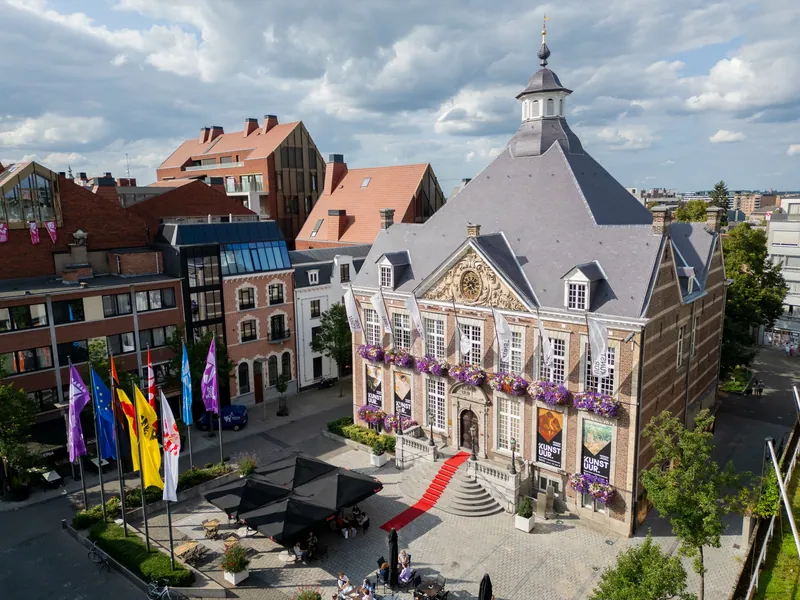 Luchtbeeld van Kunstuur Hasselt met vlaggen, bloemen en de historische daklijn